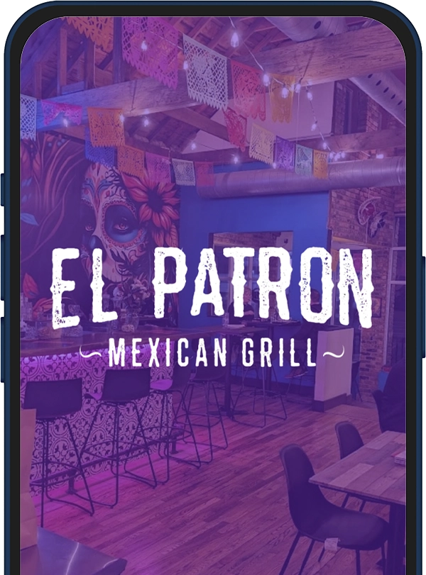 Interior of El Patron Mexican Grill: a colorful dining space with mural art, string lights, paper bunting (papel picado), and wooden tables and chairs.