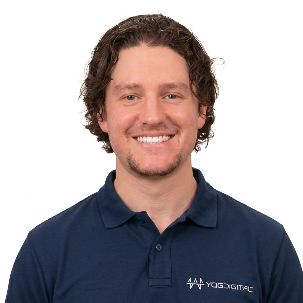 Smiling man with wavy brown hair in a navy polo shirt featuring the YGDIGITAL logo on a white background.