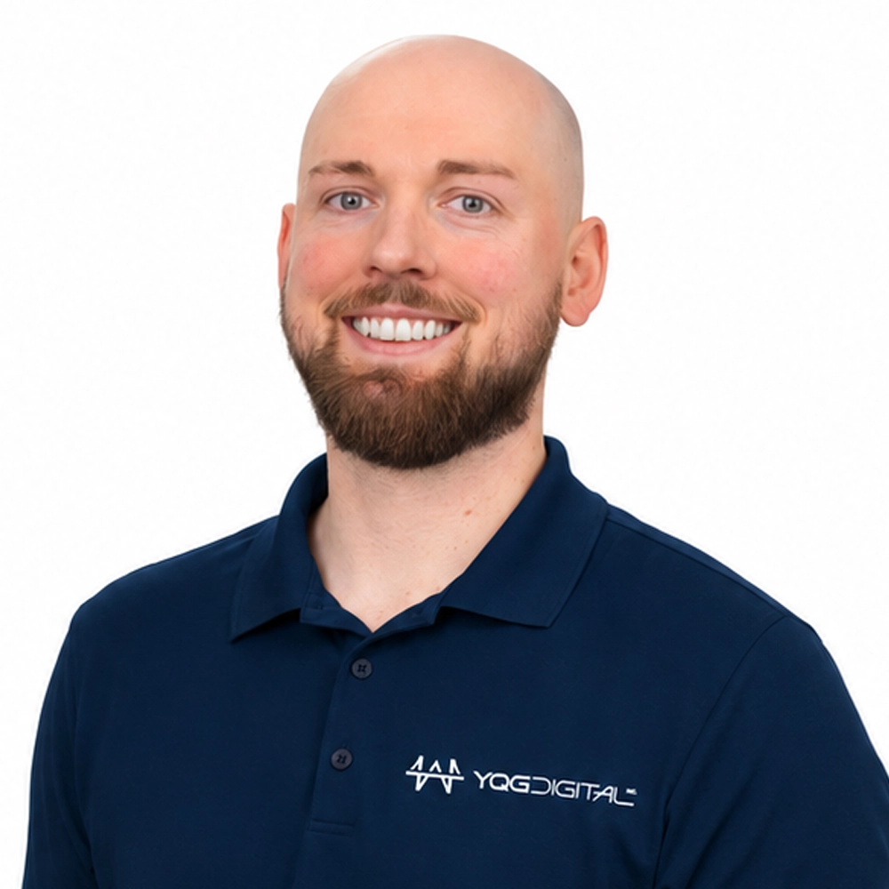 Smiling man in a navy polo with a YGDIGITAL logo on the chest against a white background.
