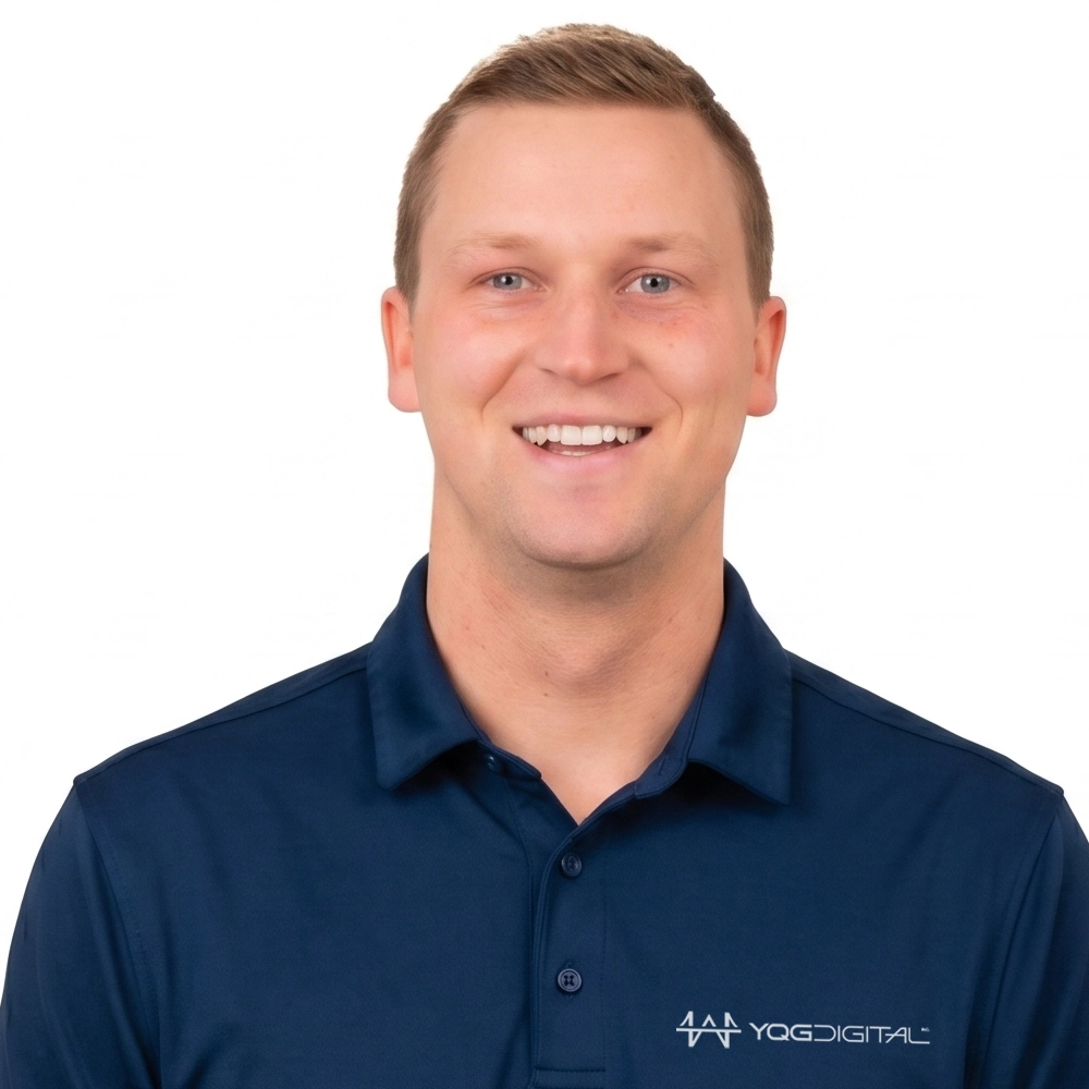Portrait of a smiling man in a navy polo shirt with a white studio background, logo readout on the chest (YGD Digital).