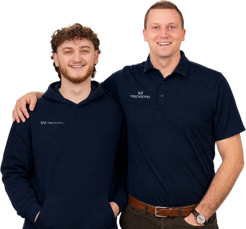 Two men in navy shirts stand side by side, one with his arm around the other's shoulder, smiling.